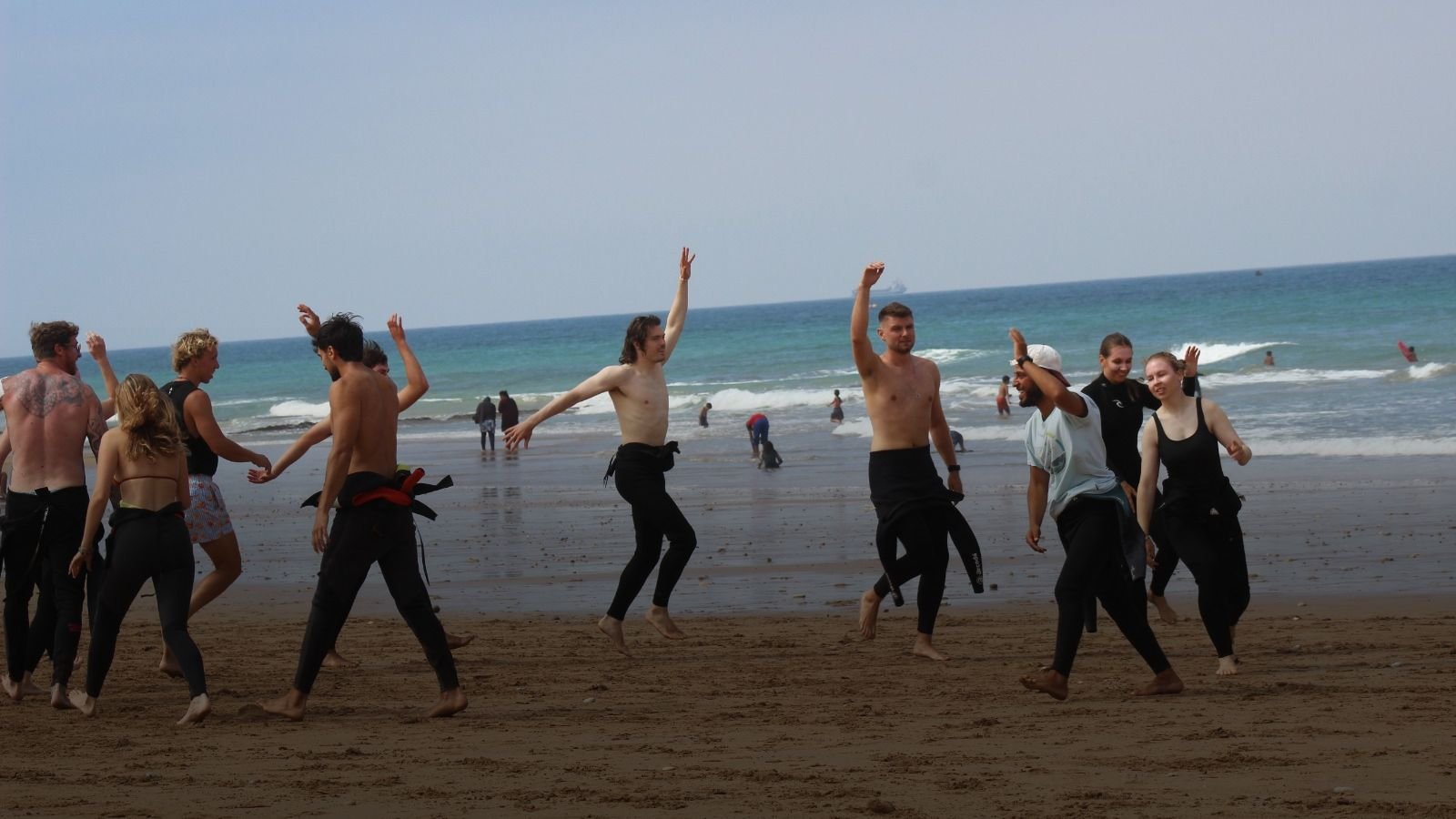 Calentamiento en grupo en la playa antes de la sesión de surf