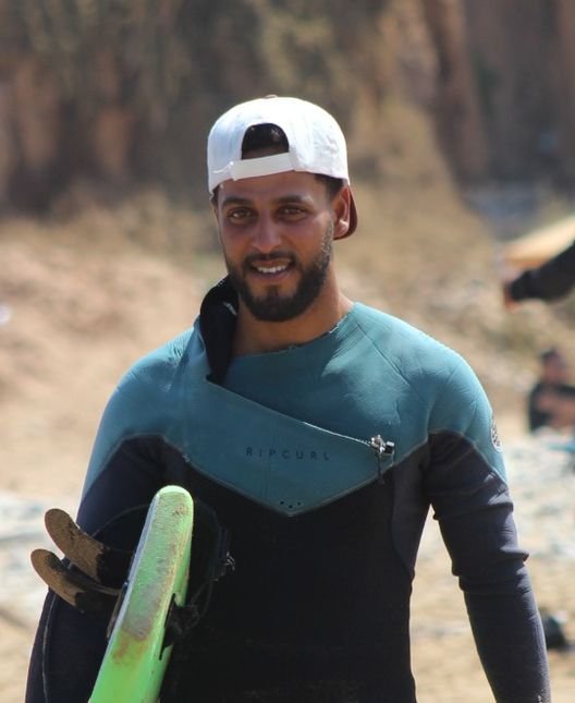 Abdul, the head coach, walking up the beach with his board
