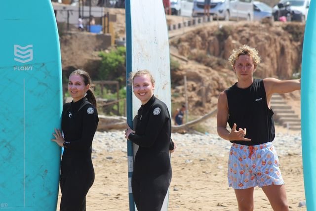 Drei Gäste mit ihren Softboards am Strand, bereit zum Rauspaddeln
