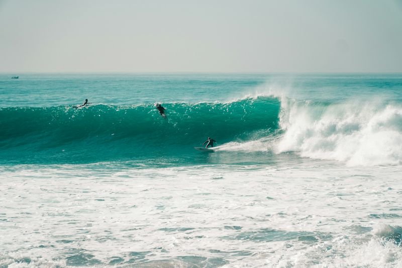 Anchor Point an einem sauberen Tag: drei Surfer auf einer langen grünen Rechten