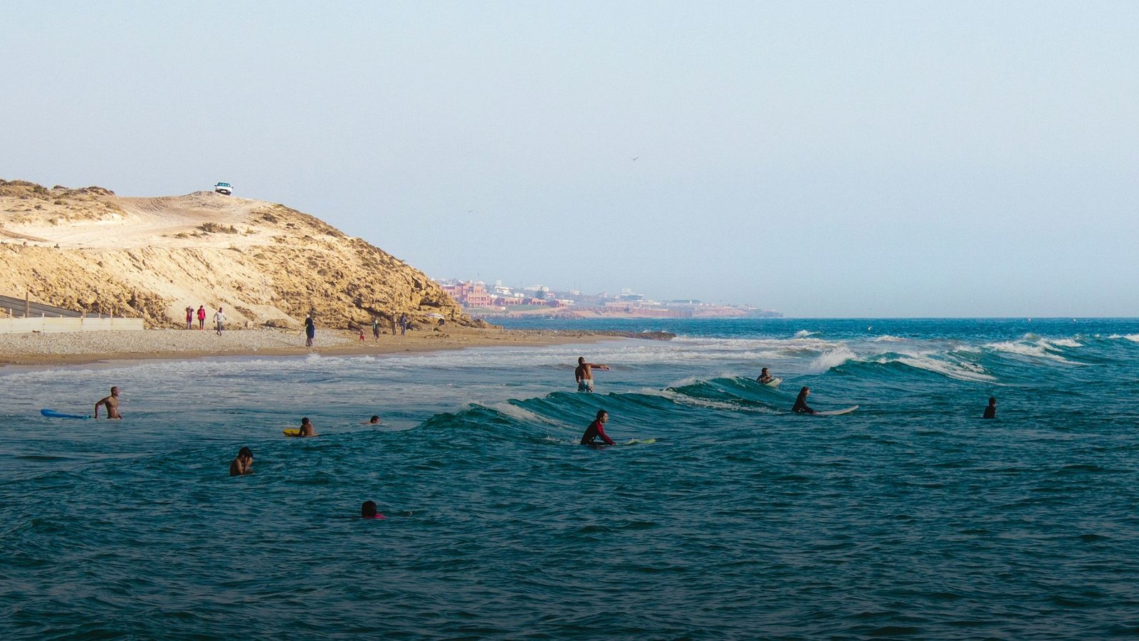 Beginners in the whitewater at Tamraght beach, the headland behind