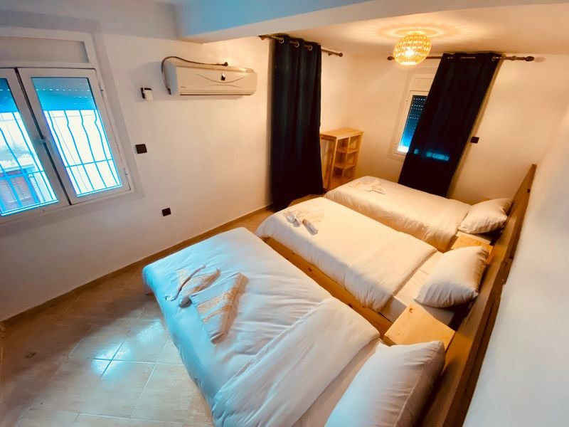 Dreibettzimmer im Hostel Taghazout: drei Einzelbetten nebeneinander unter einer Pendelleuchte