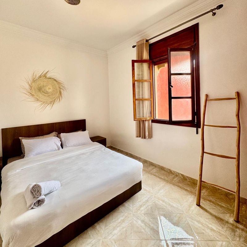 Doppelzimmer im Hostel Tamraght: Doppelbett mit gefaltetem Handtuch, offenes Fenster und ein Leiterregal aus Holz