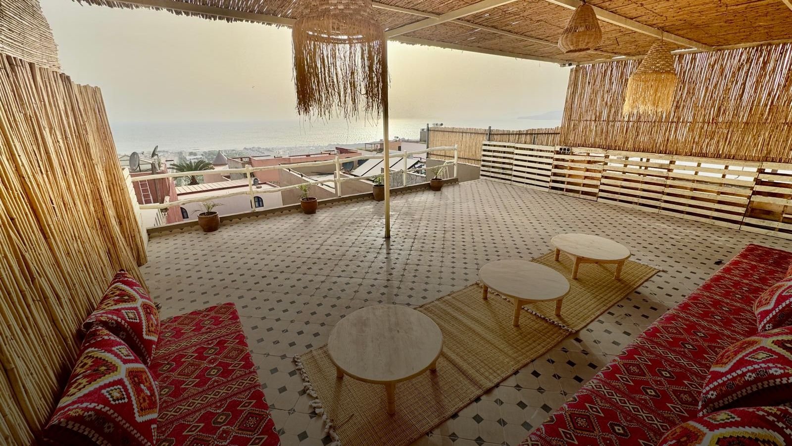 Die Dachterrasse unseres Hostels in Tamraght: Kissen und niedrige Tische unter einem Schilfdach