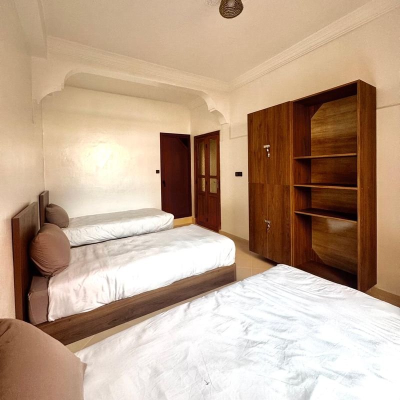 Dreibettzimmer im Hostel Tamraght: drei Einzelbetten und ein dunkler Holzschrank