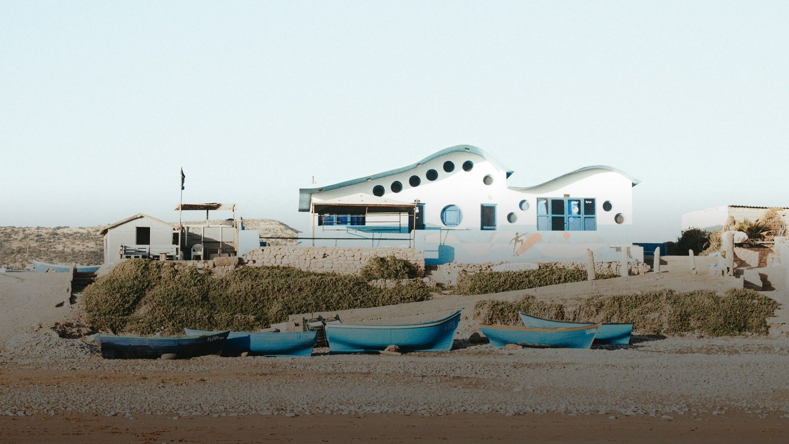 Blaue Boote und weiße Häuser am Strand von Tamraght unter klarem Himmel